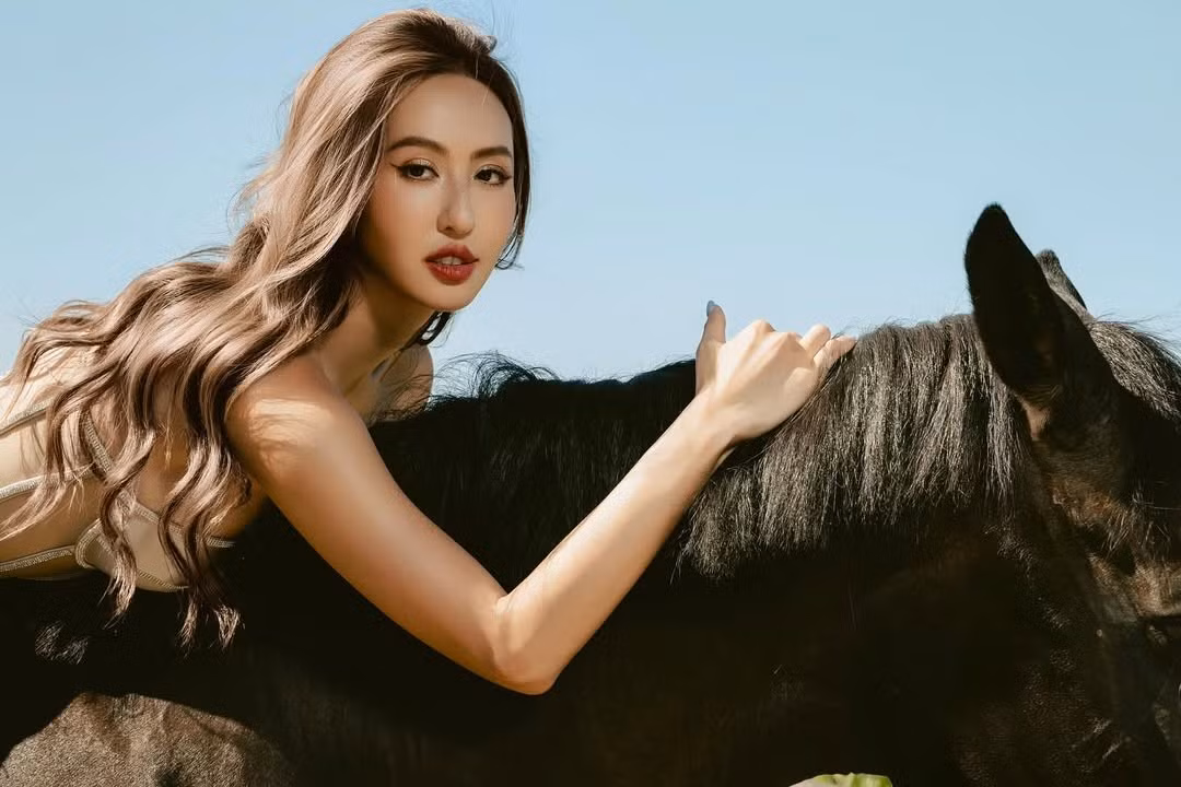 Trong bộ ảnh, người đẹp xuất hiện bên cạnh một chú ngựa đen tuyền mạnh mẽ. Trang phục mà cô diện là một chiếc corset cúp ngực màu be hoặc ánh bạc, có phần thân trên xuyên thấu và lấp lánh, mang đến cảm giác "mặc như không mặc".(Ảnh: IGNV)