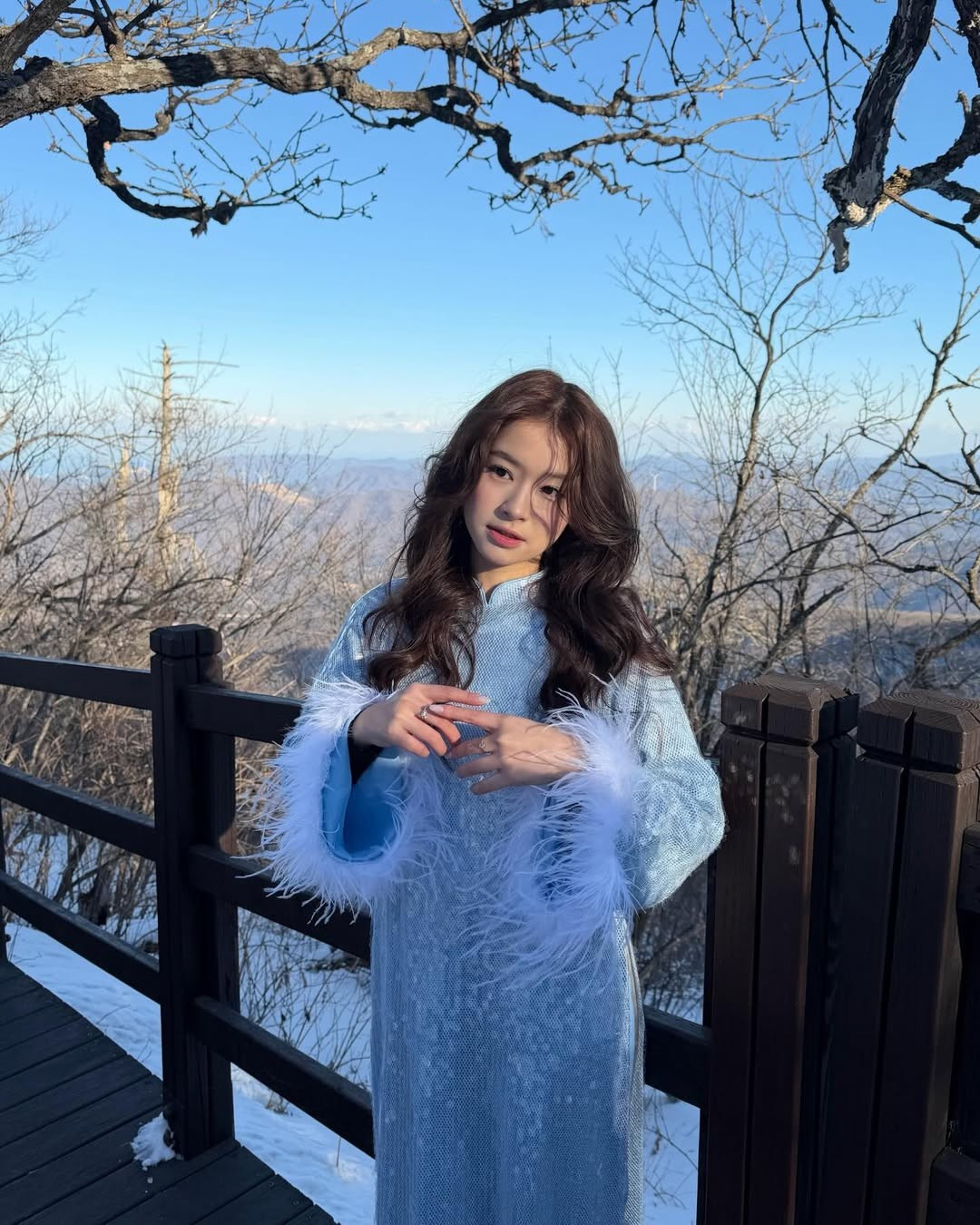 Sắc xanh của áo dài nổi bật hoàn toàn trên nền tuyết trắng tinh khôi và bầu trời trong vắt của vùng núi Balwangsan. (Ảnh: IGNV)