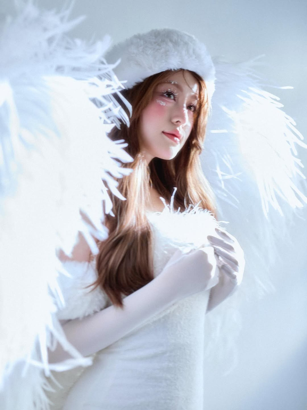 Cô diện bộ váy trắng với chất liệu lông vũ mềm mại, kết hợp cùng đôi cánh thiên thần lớn phía sau, tạo nên hình ảnh vừa thuần khiết vừa lộng lẫy. (Ảnh: IGNV)