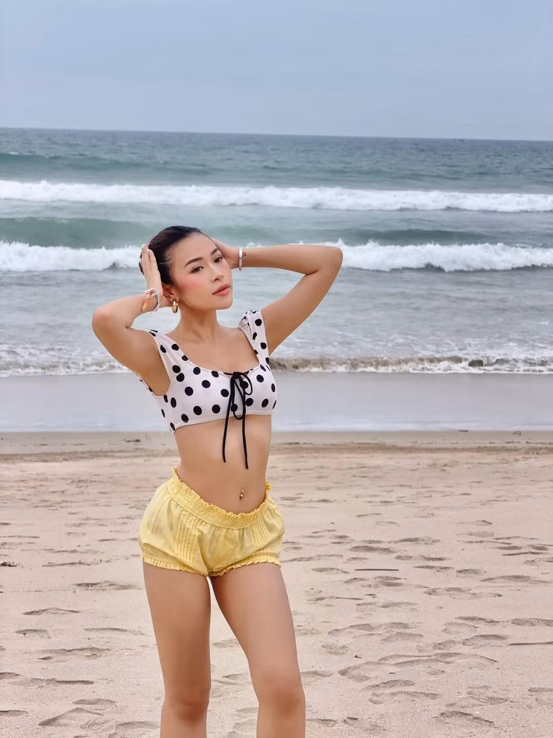 Thiết kế áo bơi với phần tay bồng nhẹ nhàng, kiểu dáng crop top cổ vuông và điểm nhấn là dây nơ buộc trước ngực, tạo nên vẻ ngoài vừa gợi cảm vừa kín đáo, đáng yêu.