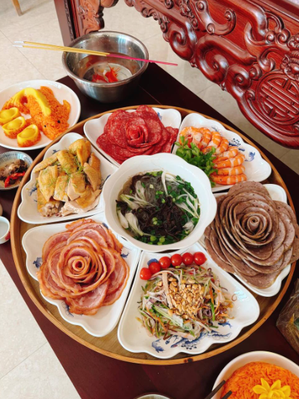 Những lát giò chả, thịt xá xíu được cuộn tỉ mỉ thành hình những đóa hoa mẫu đơn rực rỡ, tạo nên một tổng thể mâm cỗ vừa sang trọng vừa ấm cúng.