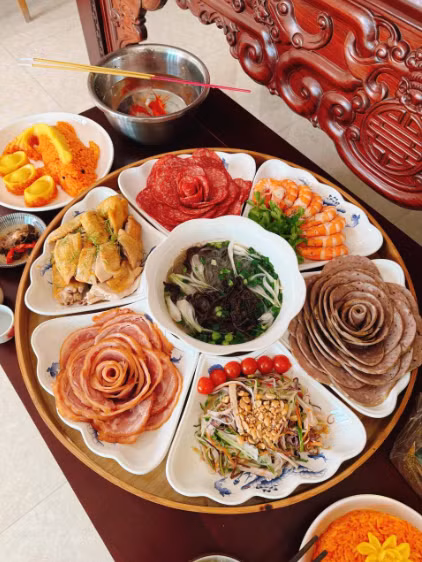 Những lát giò chả, thịt xá xíu được cuộn tỉ mỉ thành hình những đóa hoa mẫu đơn rực rỡ, tạo nên một tổng thể mâm cỗ vừa sang trọng vừa ấm cúng.