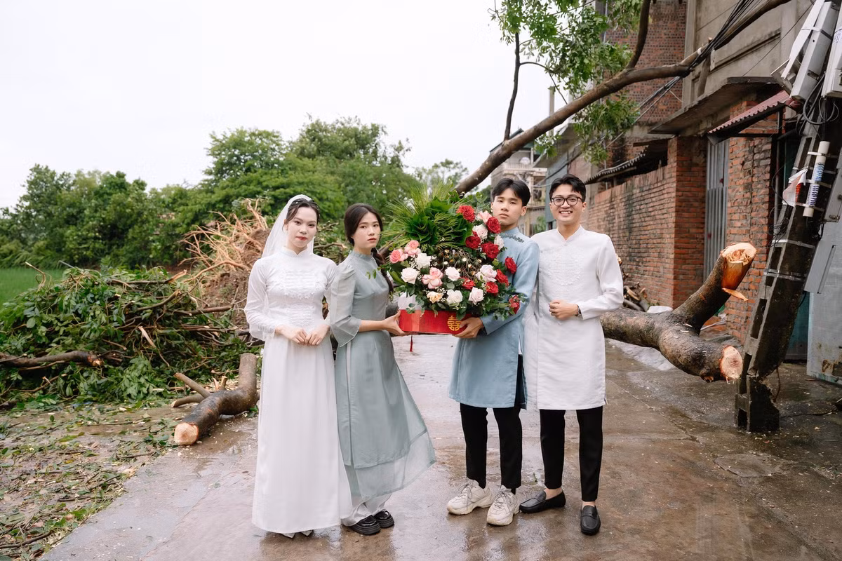 Dù phía sau là khung cảnh đường làng ngổn ngang cây đổ, xe cộ khó khăn trong việc di chuyển, nhưng nụ cười tươi tắn luôn thường trực trên môi cặp đôi.