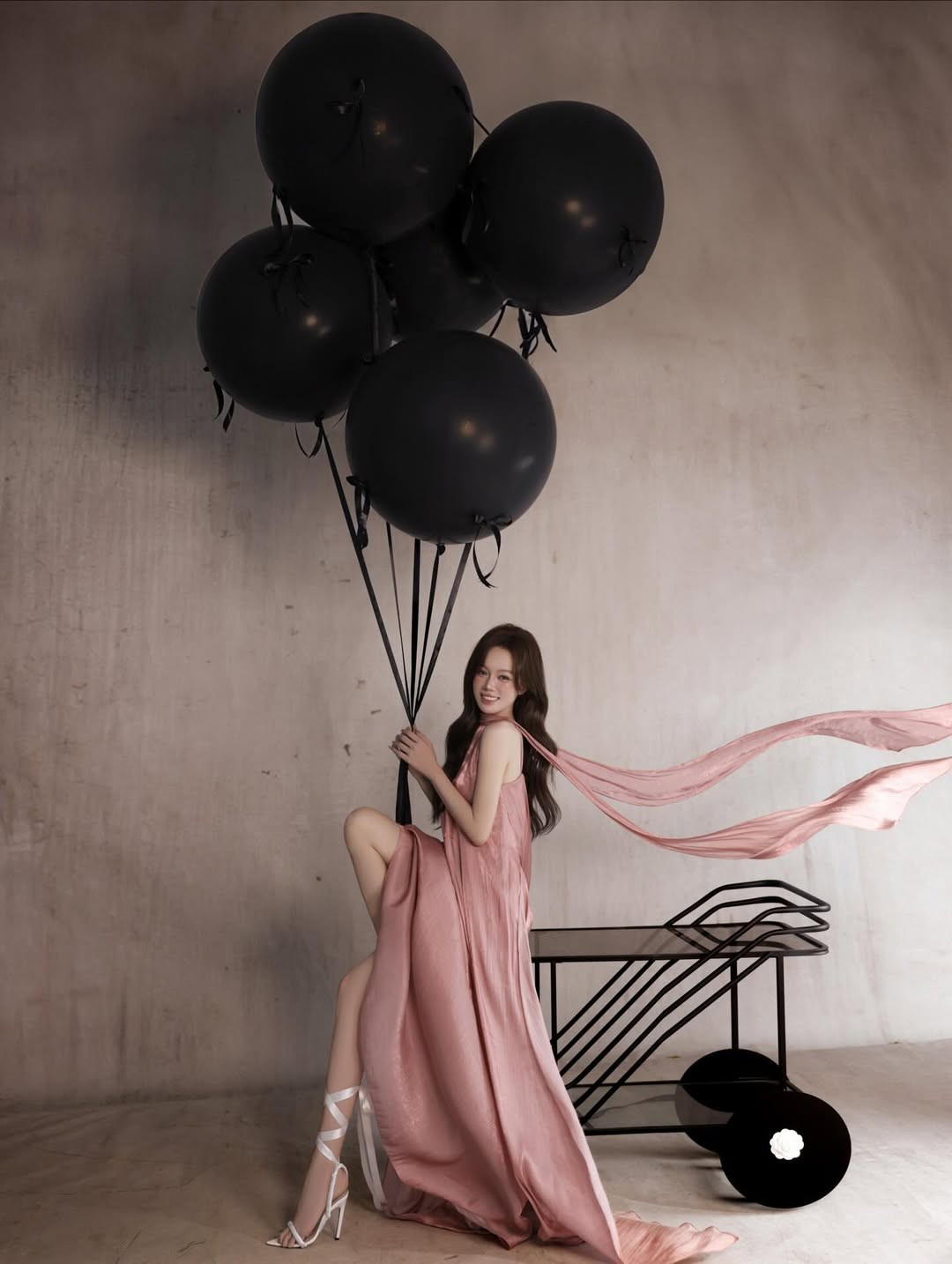 Những chùm bong bóng đen cỡ lớn cùng chiếc kệ trang trí màu đen tạo nên sự đối lập đầy nghệ thuật, làm nổi bật nhan sắc và trang phục của nhân vật chính. (Ảnh: IGNV)