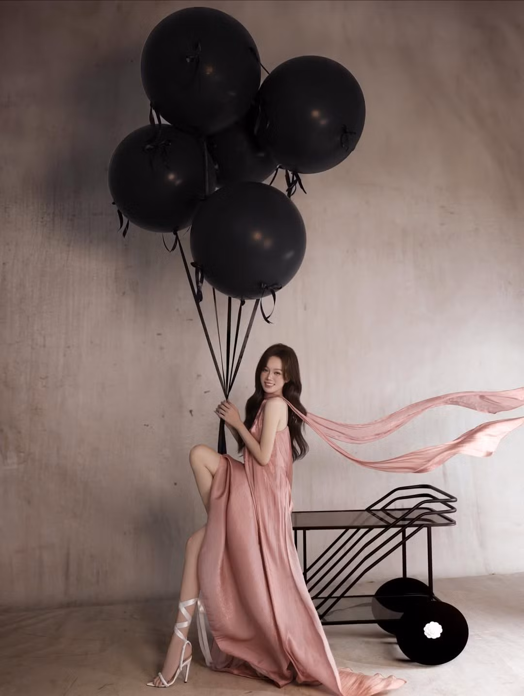 Những chùm bong bóng đen cỡ lớn cùng chiếc kệ trang trí màu đen tạo nên sự đối lập đầy nghệ thuật, làm nổi bật nhan sắc và trang phục của nhân vật chính. (Ảnh: IGNV)