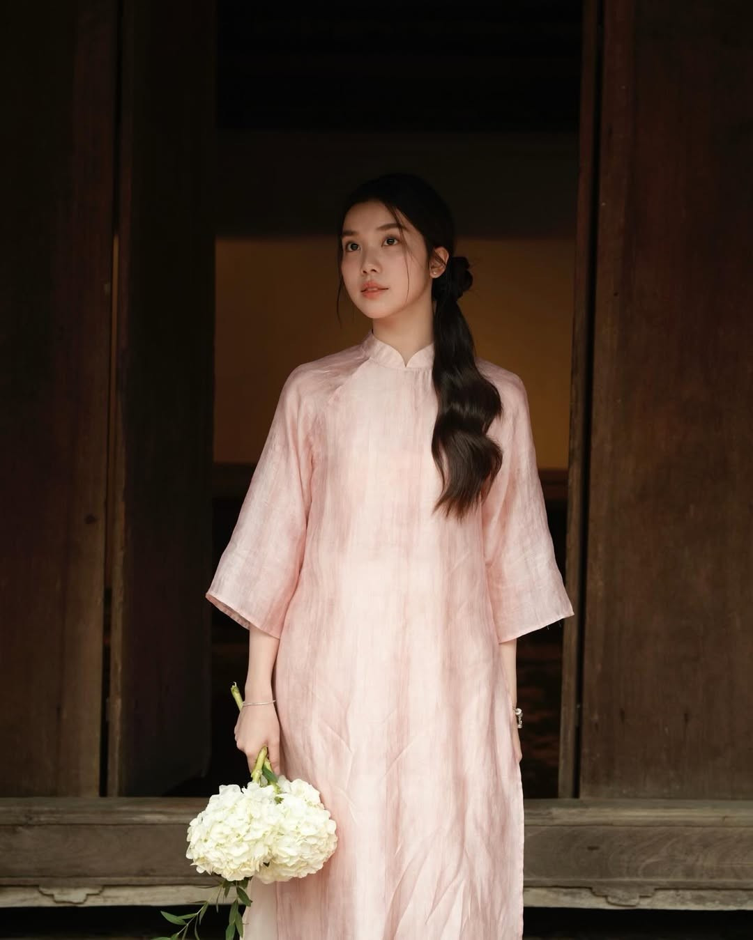 Trong bộ ảnh lần này, Trịnh Hà Vi chọn diện một chiếc áo dài cổ trụ, tay lửng, dáng suông với chất liệu vải mỏng nhẹ, có màu hồng pastel ngọt ngào, tinh tế. Chiếc áo dài được kết hợp cùng quần lụa màu trắng kem, tạo nên tổng thể hài hòa và nhẹ nhàng. (Ảnh: IGNV)