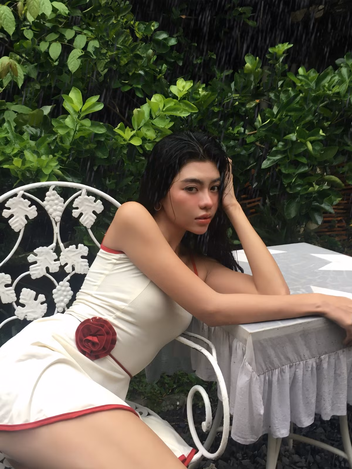 Nàng mẫu chọn một chiếc váy hai dây cúp ngực, với tông màu trắng ngà chủ đạo được viền bởi màu đỏ rượu nổi bật. Trang phục vừa tôn lên đường nét cơ thể thanh thoát, vừa mang lại cảm giác cổ điển, ngọt ngào. (Ảnh: FBNV)