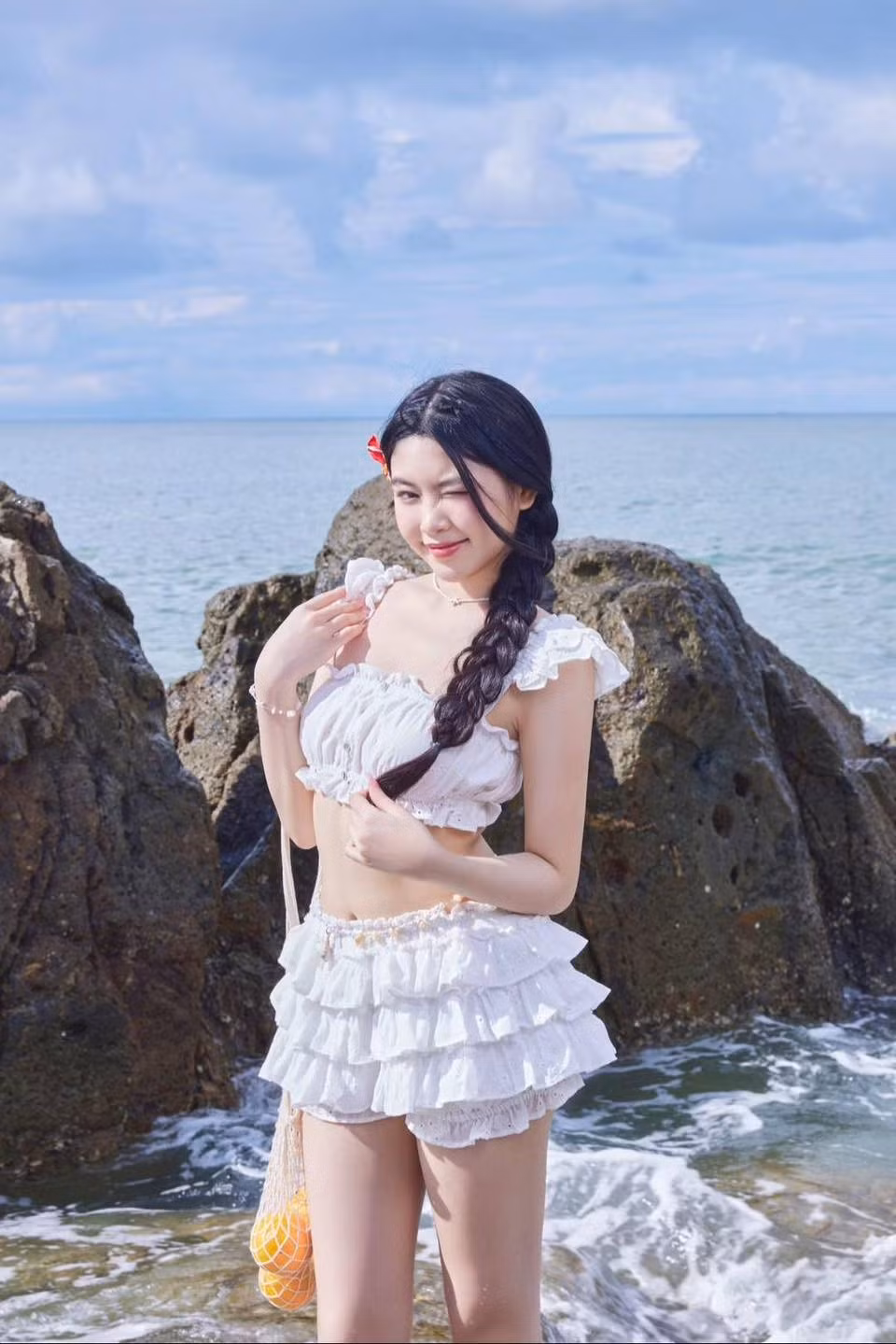 Tóc được tết bím sang một bên, kết hợp với chiếc kẹp tóc đỏ nhỏ xinh làm điểm nhấn.