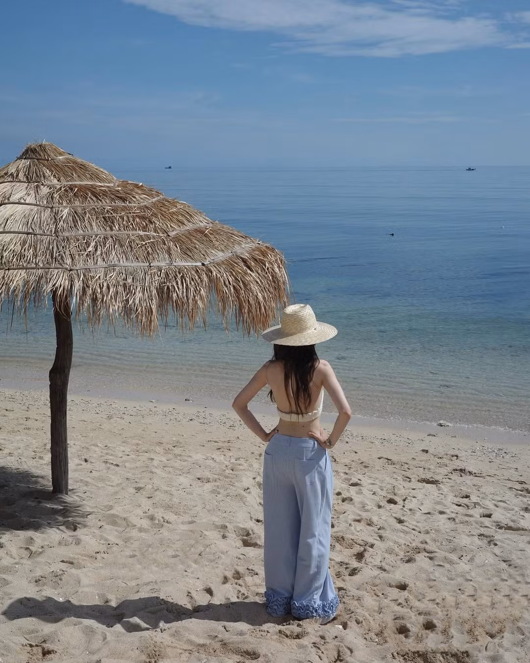 Trong loạt ảnh mới được đăng tải, cô nàng chọn cho mình một set đồ mang phong cách minimalist nhưng lại vô cùng nổi bật: áo crochet trắng dáng yếm kết hợp với quần ống rộng sọc xanh pastel – một sự kết hợp vừa cổ điển, vừa hiện đại.