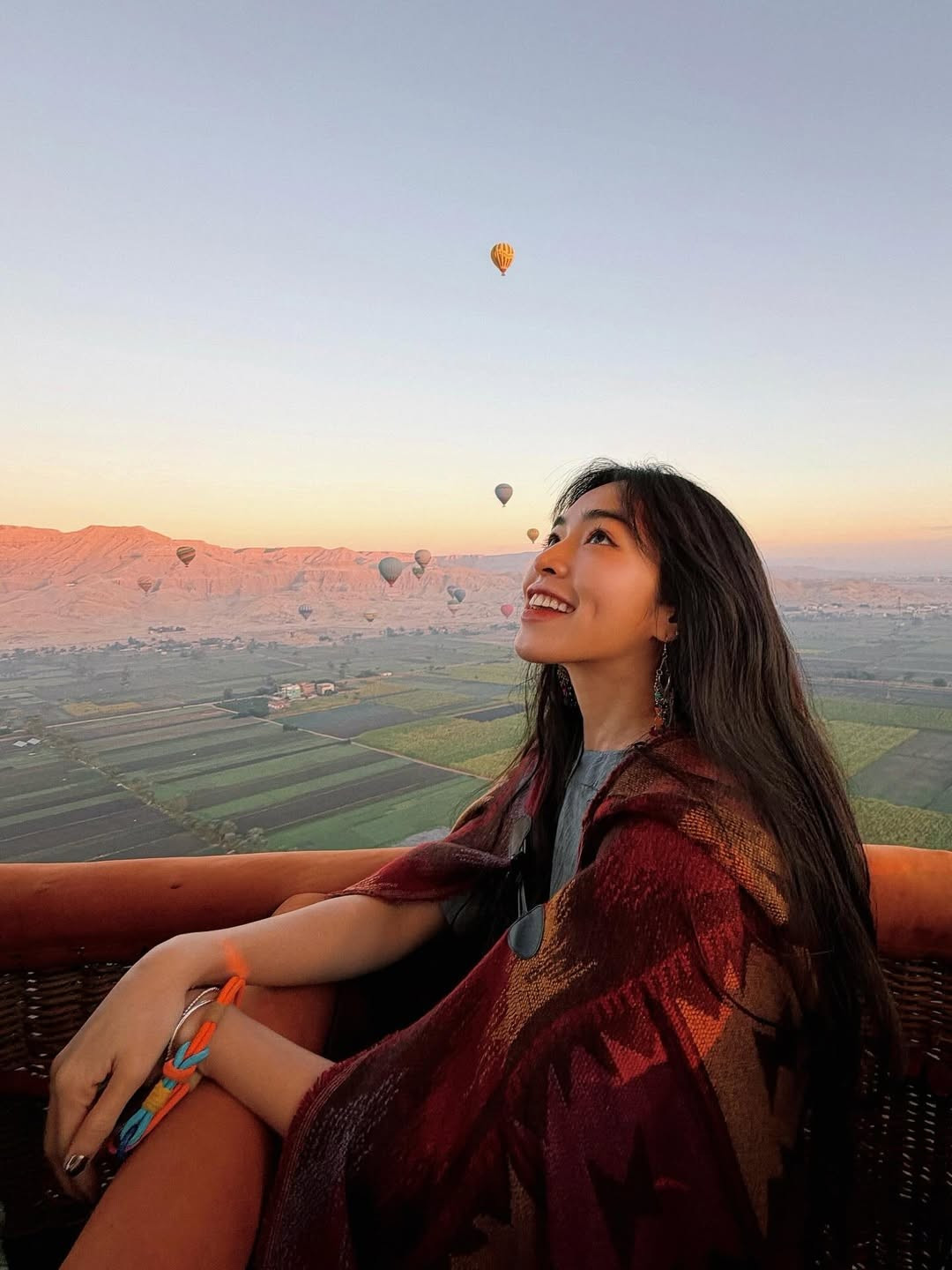 Cô nàng khéo léo chọn trang phục mang phong cách boho-chic với chiếc khăn choàng họa tiết thổ cẩm tone đỏ - nâu ấm áp, kết hợp cùng đôi khuyên mắt bản to cực kỳ ăn nhập với không gian cổ kính của vùng đất Kim tự tháp. (Ảnh: IGNV)