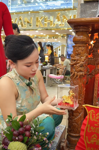 Tại tiệm vàng Vân Khánh ở Đồng Tháp, ngay từ tờ mờ sáng, rất nhiều người đã chờ sẵn để mua vàng cầu may. Minh Thư cùng mẹ ruột đã có mặt từ sớm để thực hiện nghi thức cúng vía Thần Tài, đồng thời điều phối nhân viên và trực tiếp tư vấn cho khách hàng.