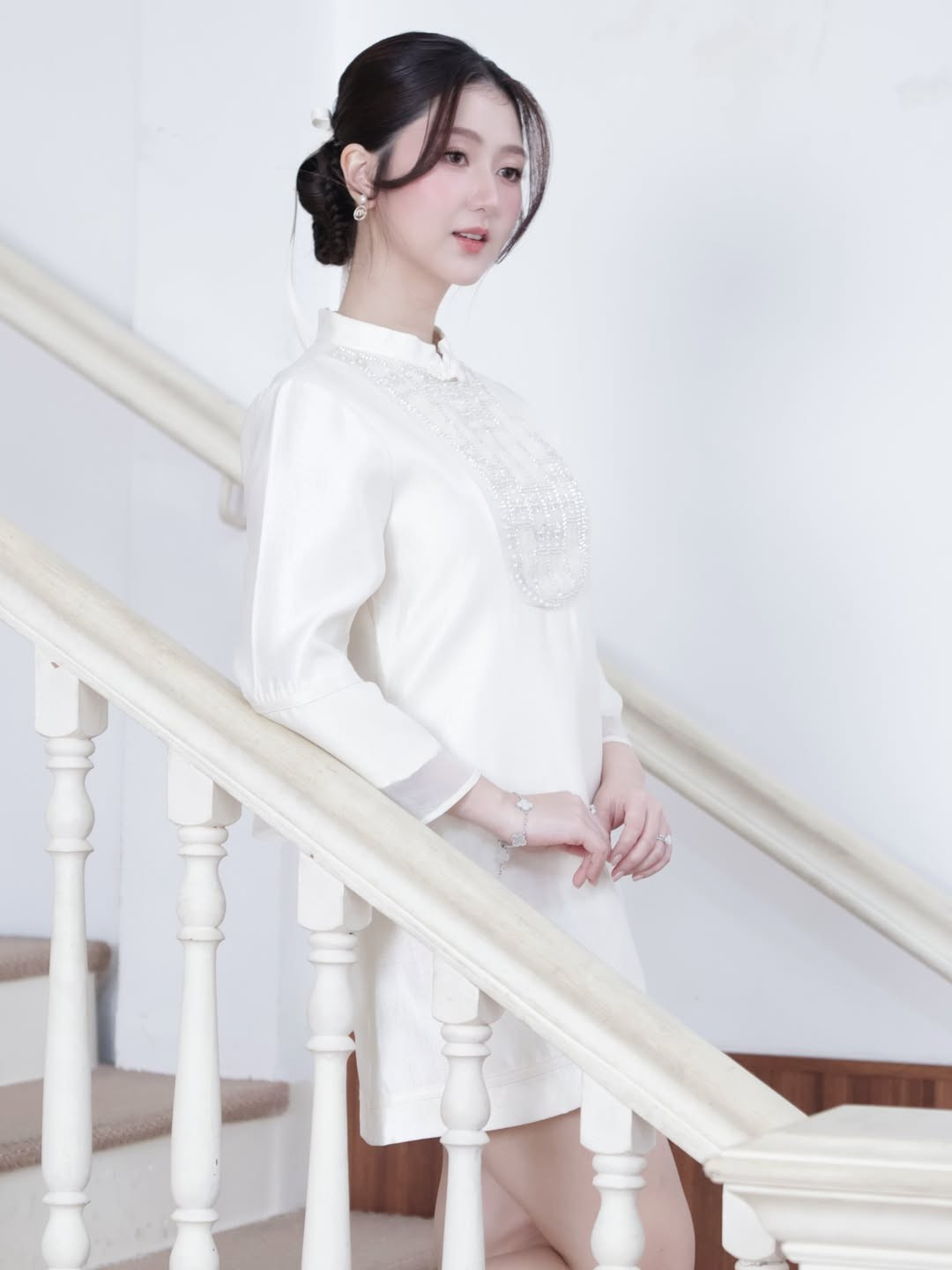 Cô nàng chọn kiểu tóc búi gọn gàng phía sau, điểm xuyết bằng dải ruy băng trắng thắt nơ dài. Kiểu tóc này giúp khoe trọn đường nét gương mặt thanh tú và phần cổ áo thanh lịch. (Ảnh: IGNV)