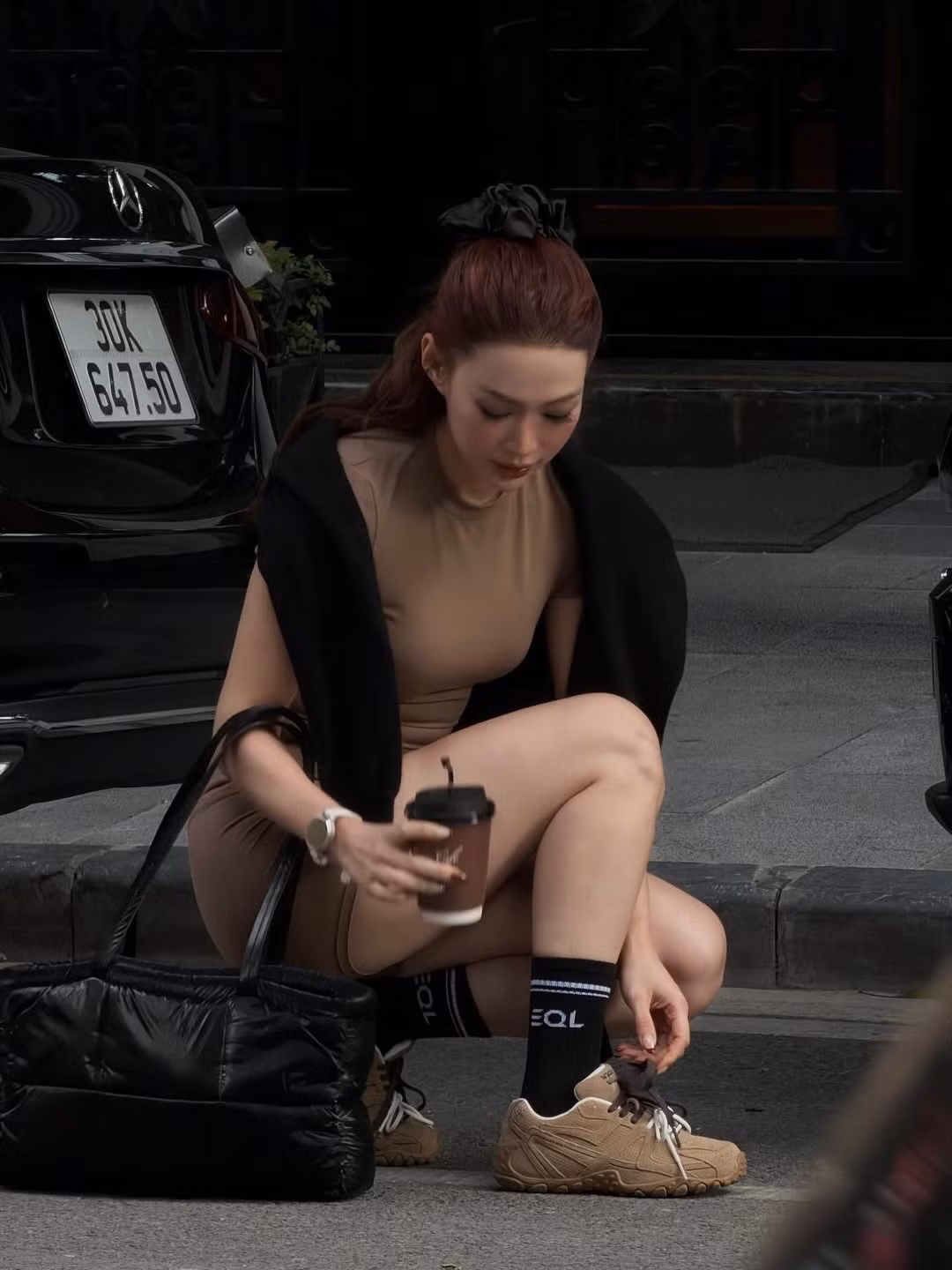 Mái tóc dài màu nâu đỏ được cô nàng buộc nửa đầu năng động làm nổi bật khuôn mặt thanh tú và thần thái rạng rỡ. Túi xách phồng lớn màu đen và chiếc đồng hồ đeo tay sành điệu giúp nâng tầm set đồ tập gym thành một outfit street style cá tính. (Ảnh: IGNV)