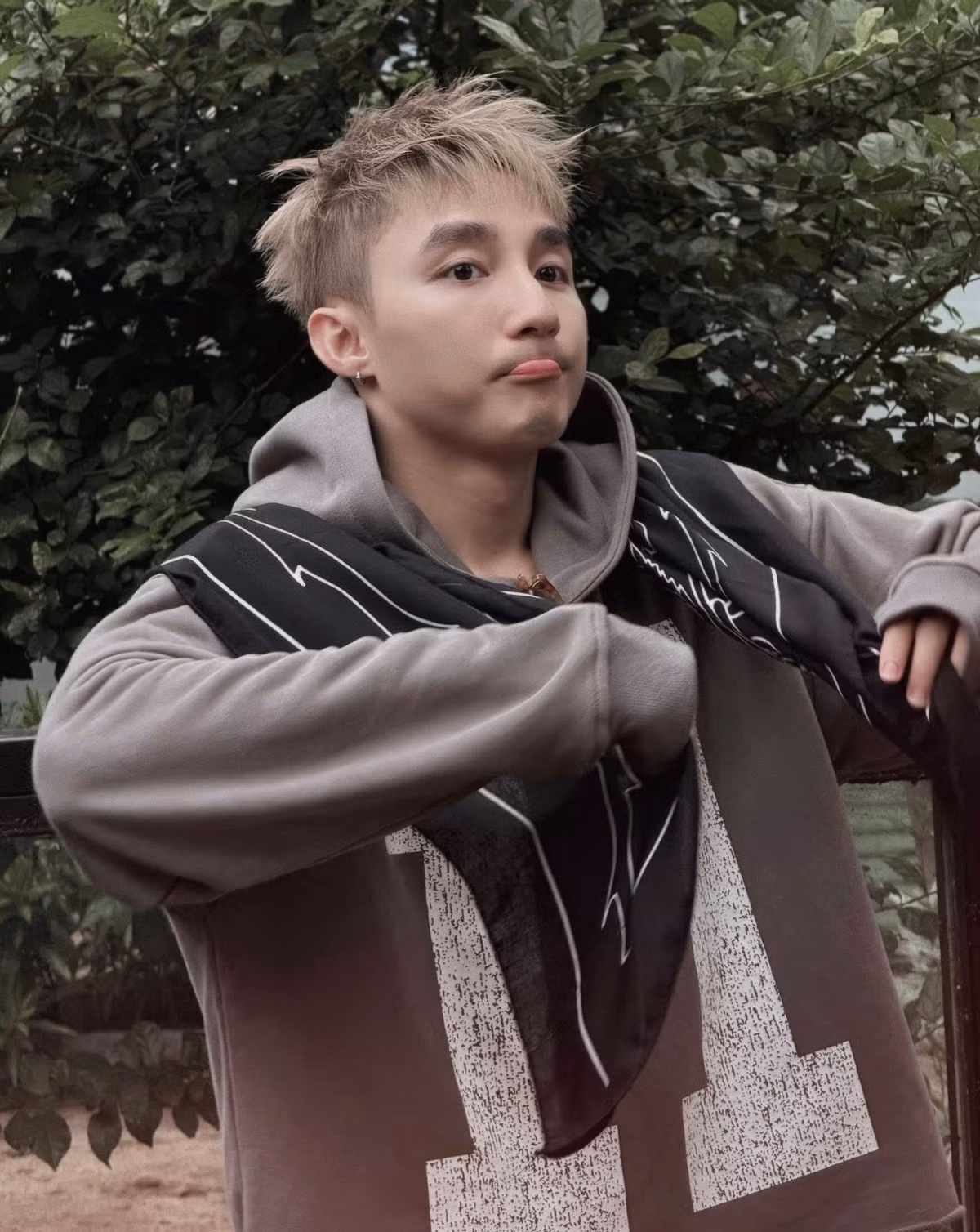 Về phong cách thời trang, Sơn Tùng M-TP vẫn giữ vững sự cá tính và năng động quen thuộc. Anh diện áo hoodie màu xám có họa tiết chữ số lớn, phối cùng quần jeans lửng màu hồng và đi giày thể thao màu kem. (Ảnh: FBNV)