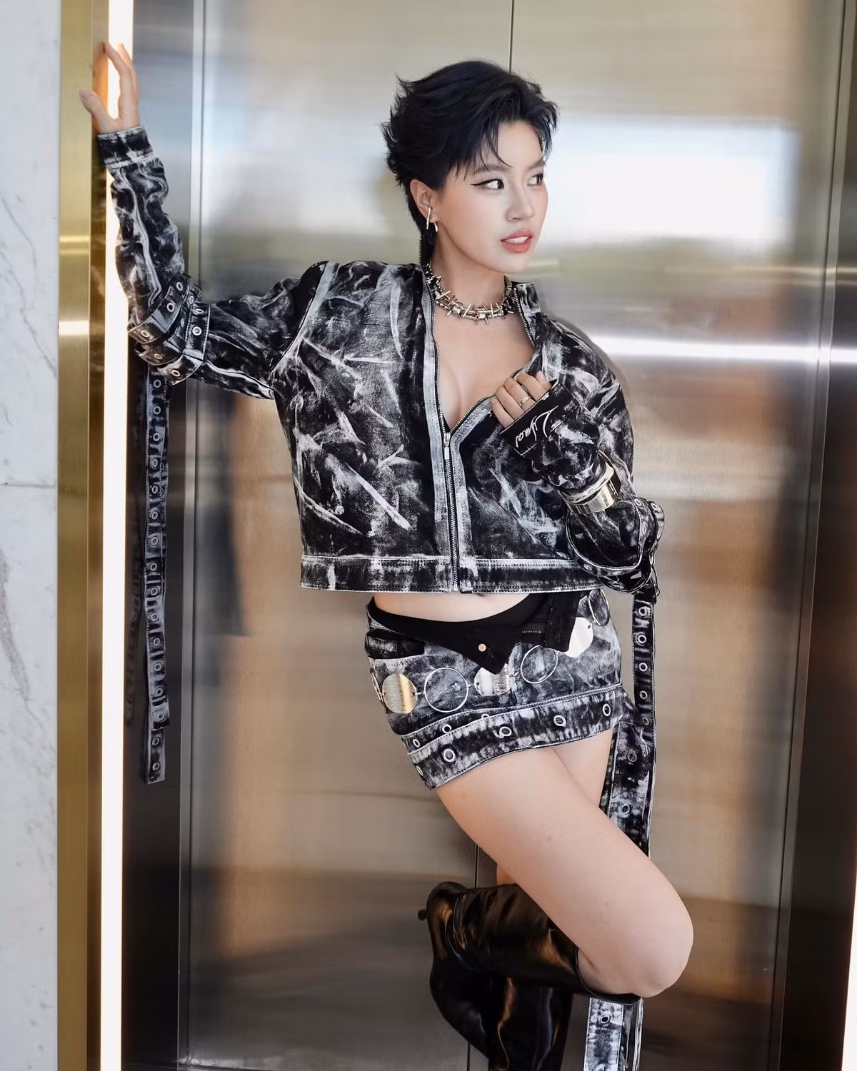 Cô mix thêm vòng cổ gai cá tính, khuyên tai ánh bạc cùng boots da cao cổ “ngầu đét”. Tất cả tạo nên một visual bùng nổ đúng chuẩn “bad gal”.