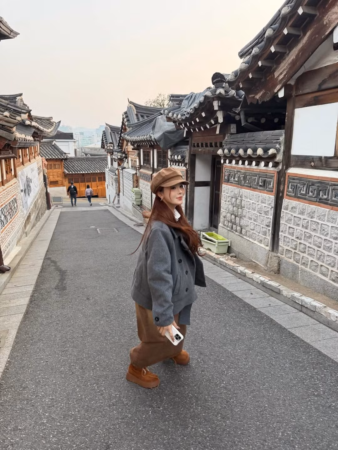 Nàng Tiktoker cũng dạo bước trên con đường lát đá giữa những ngôi nhà truyền thống Hanok với kiến trúc mái ngói cong và tường đá đặc trưng. Khung cảnh cổ kính này càng tôn lên nét duyên dáng, lãng mạn của cô. (Ảnh: IGNV)