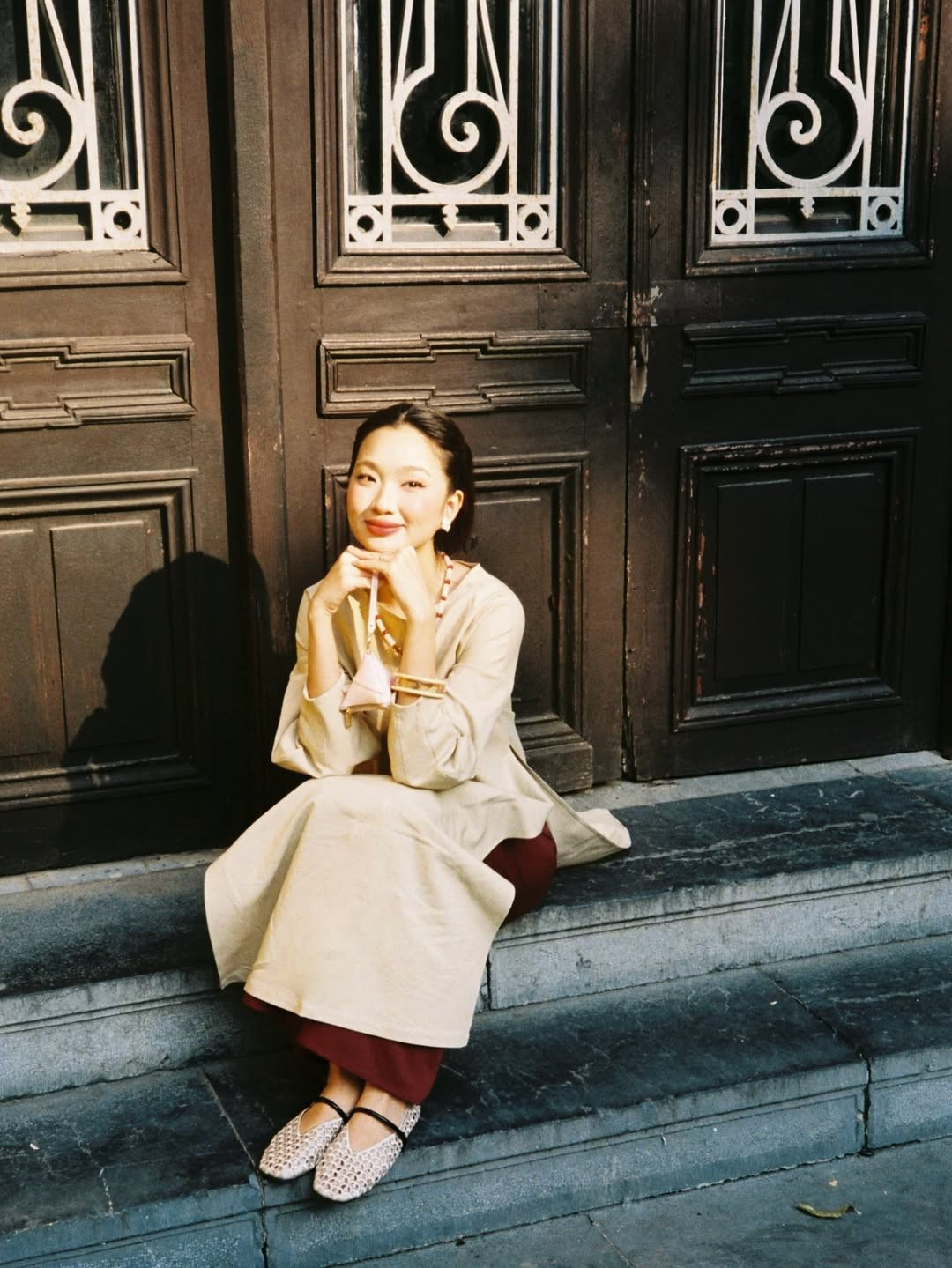 Trong bộ ảnh lần này, Chái Chanh lựa chọn thiết kế áo dài dáng suông - xu hướng đang "làm mưa làm gió" mùa Tết 2026. Tông màu be trung tính kết hợp cùng quần ống rộng màu đỏ đô tạo nên sự tương phản sang trọng, vừa giữ được nét truyền thống vừa mang hơi thở thời đại. (Ảnh: IGNV)