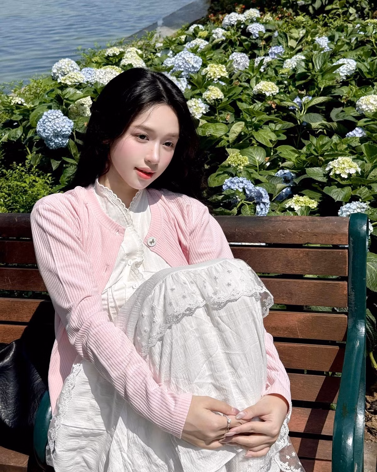 Những bức ảnh của Karty Chang không chỉ thu hút bởi nhan sắc rạng rỡ, làn da trắng hồng mà còn bởi thần thái tự nhiên, từ động tác nhẹ nhàng ngồi trên ghế gỗ, tạo hình trái tim dễ thương, cho đến ánh mắt mơ màng hướng về phía hồ nước. (Ảnh: FBNV)