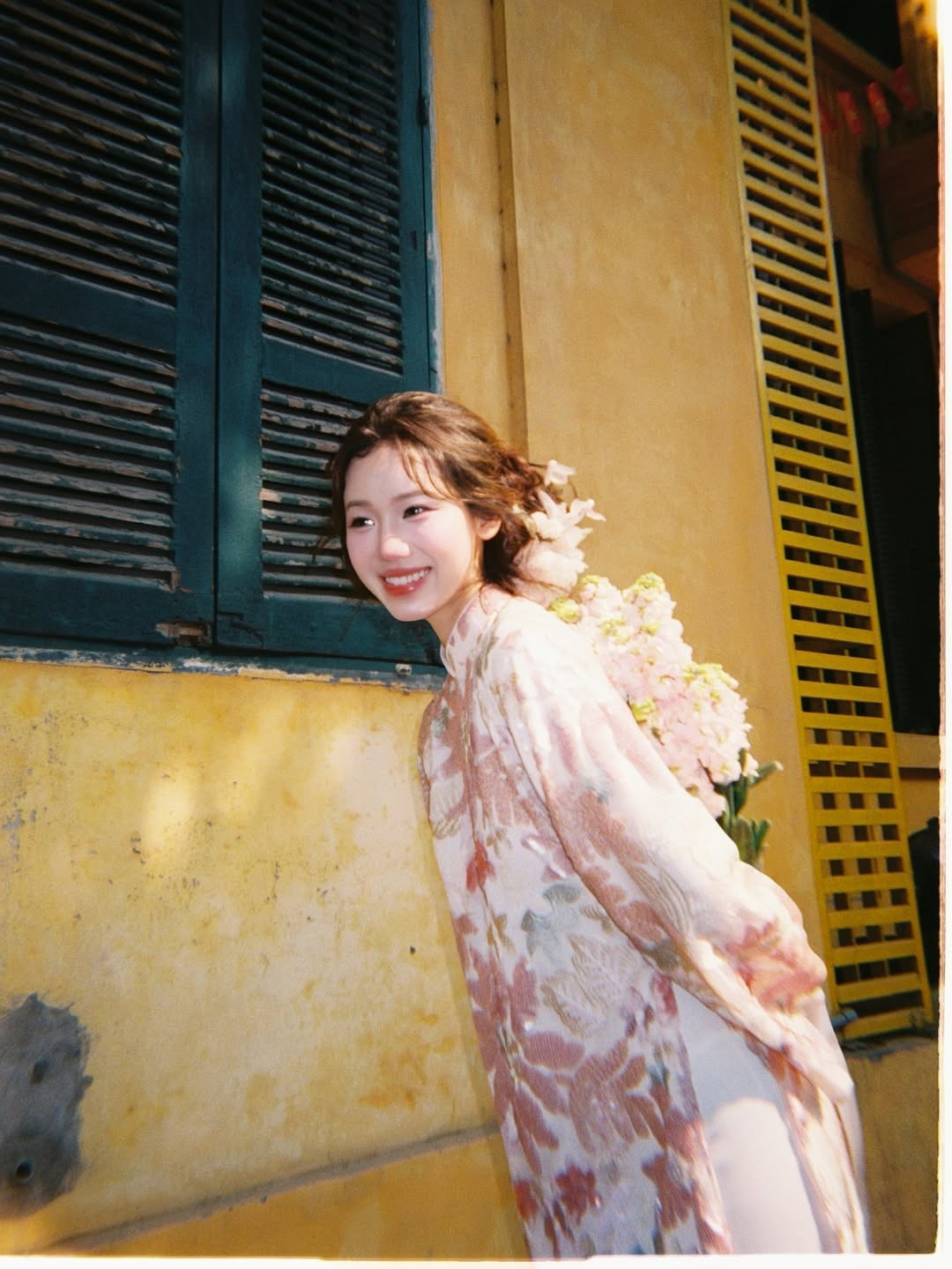 Một trong những yếu tố quan trọng nhất tạo nên vẻ ngoài thoát tục của Meichan trong bộ ảnh chính là kiểu tóc được đầu tư kỹ lưỡng. Những nhành hoa lan trắng và hồng được cài khéo léo phía sau tai, tạo sự kết nối đồng điệu với bó hoa trên tay và họa tiết trên tà áo dài. (Ảnh: IGNV)