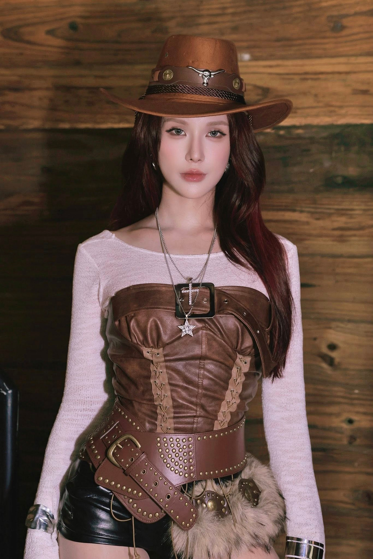 Cô diện áo dệt kim màu trắng kem, kết hợp cùng áo corset bằng da màu nâu với những chi tiết đan dây và đinh tán nổi bật. (Ảnh: IGNV)