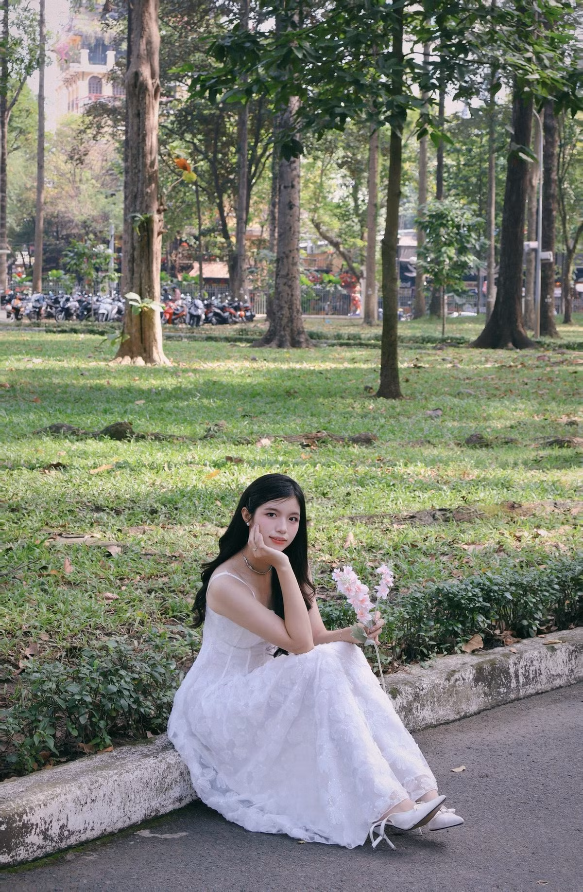 Nhành hoa hồng pastel trên tay trở thành điểm nhấn hoàn hảo, giúp bộ ảnh thêm phần thơ mộng giữa không gian xanh mướt phía sau. (Ảnh: IGNV)