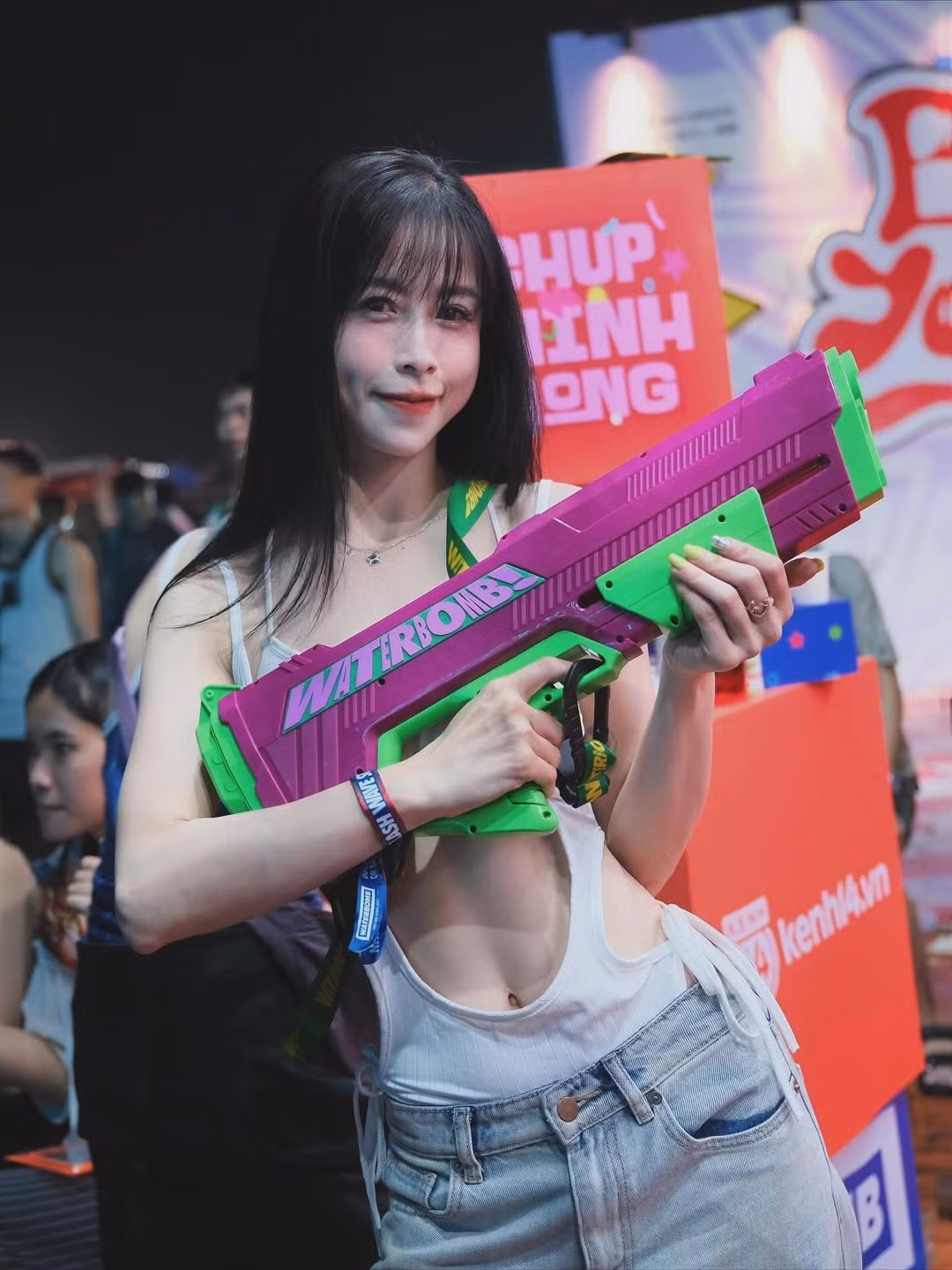 Không thể thiếu "vũ khí" Waterbomb đặc trưng là khẩu súng nước màu hồng tím neon và xanh lá nổi bật. Nữ vận động viên liên tục tạo dáng chuyên nghiệp, toát lên thần thái rạng rỡ, cuốn hút giữa đám đông. (Ảnh: IGNV)