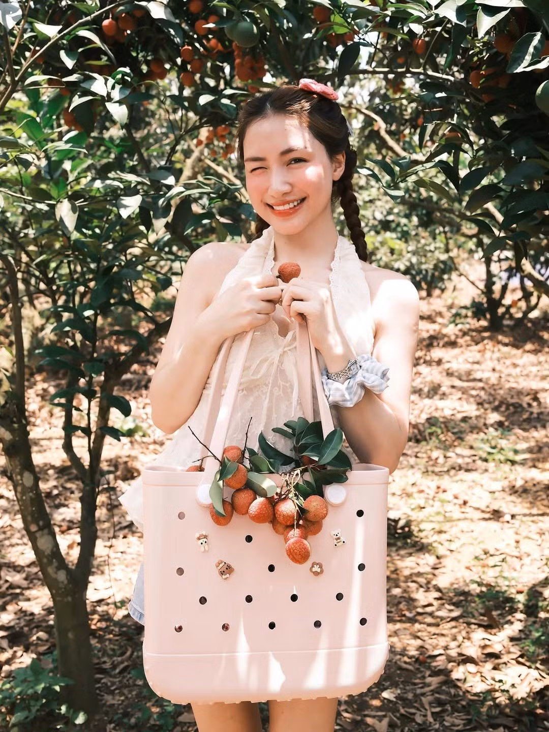 Trong một bức ảnh, Hòa Minzy cười tươi rạng rỡ, nháy mắt tinh nghịch khi cầm trên tay chùm vải chín mọng, như đang mời gọi người xem cùng thưởng thức. Nụ cười "thương hiệu" của cô nàng với đôi mắt híp lại và khóe miệng duyên dáng luôn là điểm sáng, mang đến năng lượng tích cực cho người đối diện.