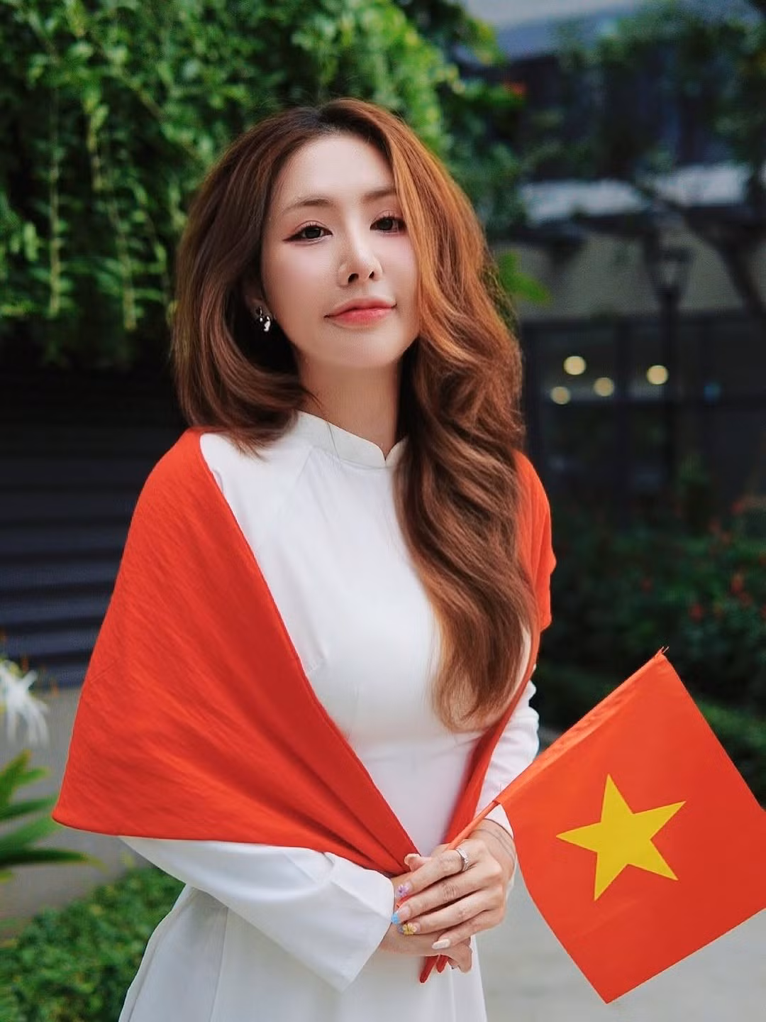 Cô chọn thiết kế áo dài màu trắng tinh khôi, kết hợp với khăn choàng đỏ nổi bật có hình ngôi sao vàng, tái hiện lá cờ Tổ quốc một cách đầy sáng tạo và ý nghĩa. (Ảnh: FBNV)