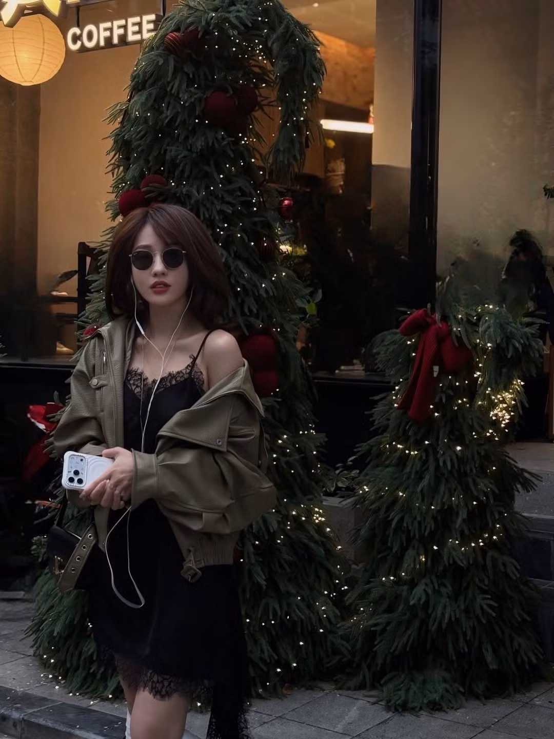 Điểm nhấn hoàn hảo là chiếc áo khoác da màu xanh olive được khoác hờ trên vai, tạo nên sự đối lập thú vị giữa nét quyến rũ của chiếc váy lụa và sự mạnh mẽ, "cool ngầu" của chất liệu da, đồng thời giữ ấm vừa đủ cho không khí se lạnh cuối năm. (Ảnh: IGNV)