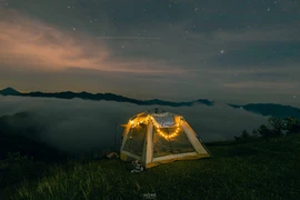 Từ đỉnh Tăk Pổ, du khách có thể phóng tầm mắt ra xa, thấy toàn cảnh bản làng nhỏ bé nằm ẩn mình trong sương. Những mái nhà sàn nằm nép bên triền núi, khói bếp buổi sớm len lỏi qua tán cây – tất cả tạo nên khung cảnh nên thơ khiến bất cứ ai cũng muốn dừng lại thật lâu để ngắm nhìn. Ảnh Nguyễn Thanh Cường