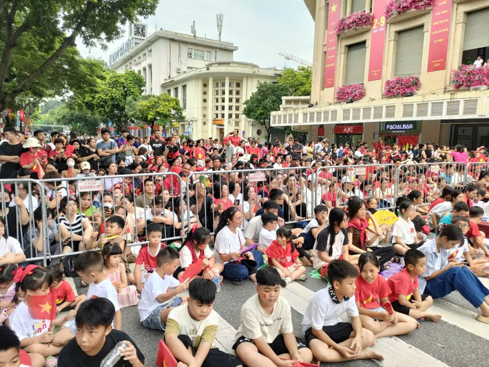Hàng ngàn người dân, bao gồm cả trẻ em ngồi ở khu vực ngã tư Tràng Tiền - Đinh Tiên Hoàng để theo dõi buổi sơ duyệt cấp Nhà nước Lễ diễu binh, diễu hành kỷ niệm 80 năm Cách mạng Tháng Tám thành công và Quốc khánh 2/9 (nhiệm vụ A80).
