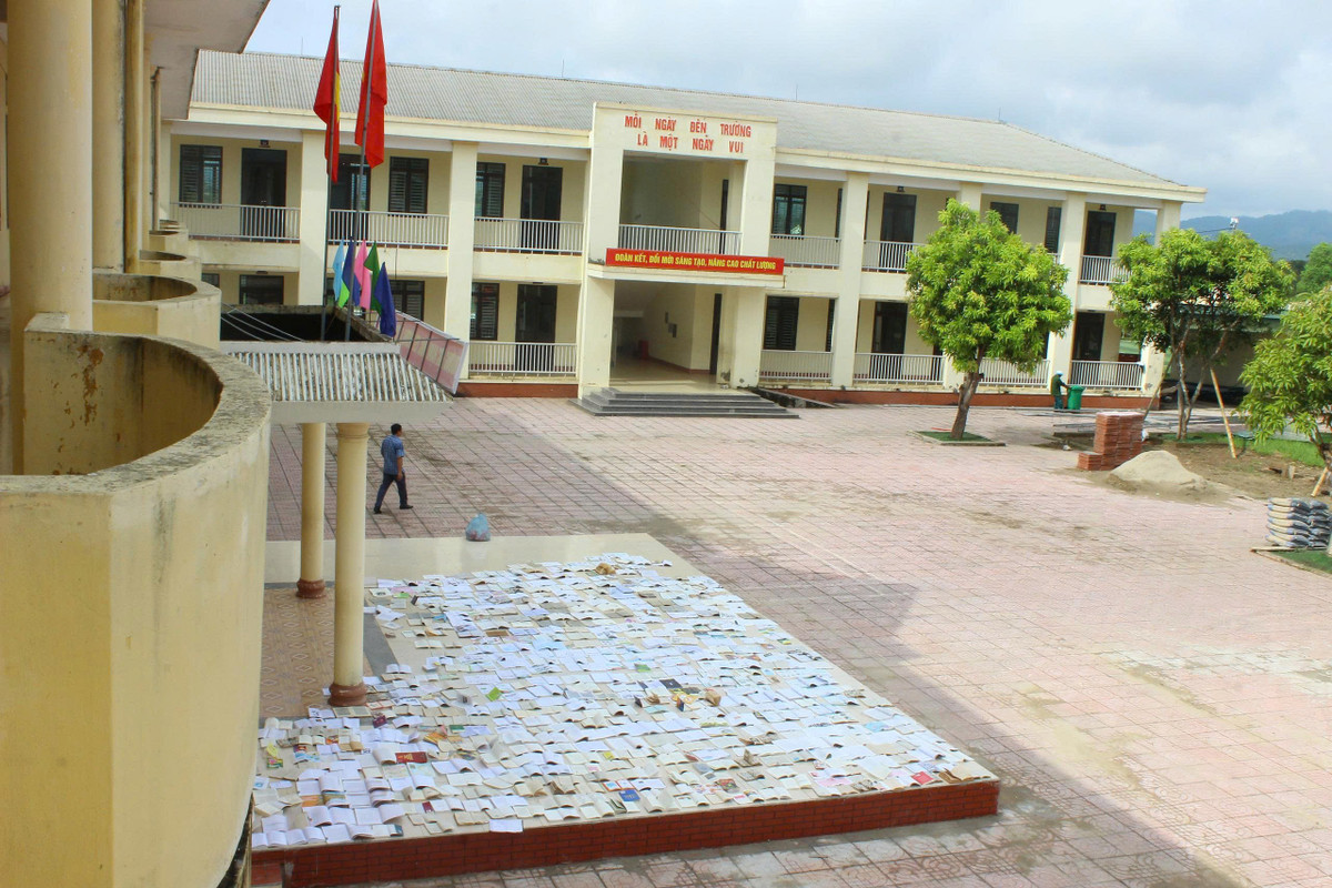 Tranh thủ thời tiết nắng ráo, các cô giáo trường THCS Sơn Lộc lật dở từng trang sách để hong phơi cho học sinh.