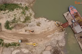 Xe tải nhộn nhịp vào bãi vật liệu trong đất dự án để đổ đất xuống sà lan.