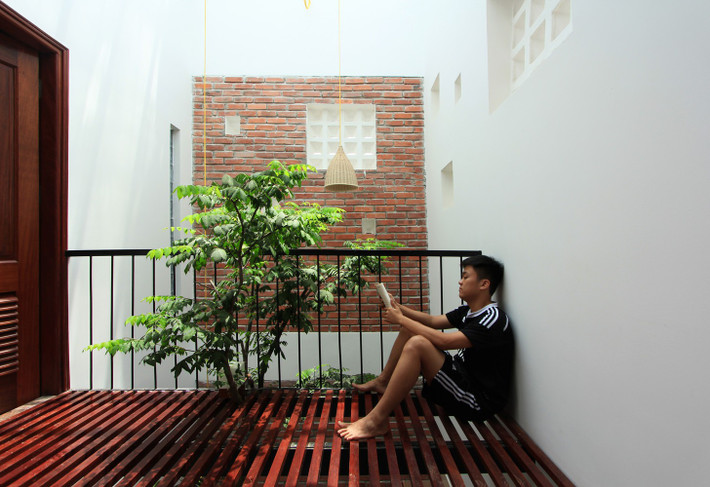 Tận dụng khoảng không của giếng trời sau nhà, kiến trúc sư thiết kế thêm ban công nhỏ ở tầng 2 để hưởng trọn ánh sáng từ giếng trời. Tại đây, gia chủ có thể thư giãn, uống tách trà hay đọc sách. Ảnh: My Anh Nguyen