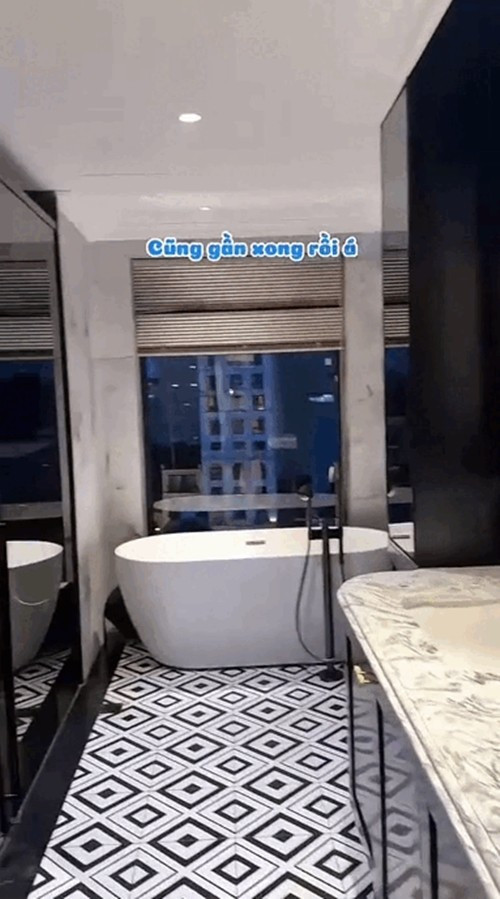 Nhà vệ sinh rộng, phối màu trắng - đen đối lập tạo cảm giác sang trọng. Điểm nhấn là bồn tắm cạnh cửa sổ lớn với tầm nhìn cực chill. Ảnh chụp màn hình