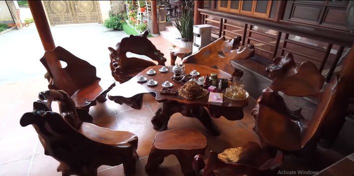Ngoài hiên, gia chủ đặt sập gỗ gõ đỏ và bộ bàn ghế gỗ lim. Ảnh chụp màn hình NhaTo