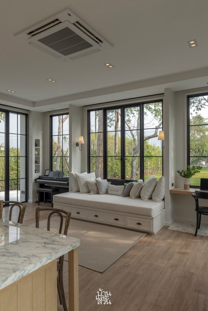 Không gian bên trong thiết kế mở, sử dụng toàn bộ cửa kính. Phòng khách có sofa giường lớn để gia chủ nghỉ ngơi. Ảnh: Baanlaesuan