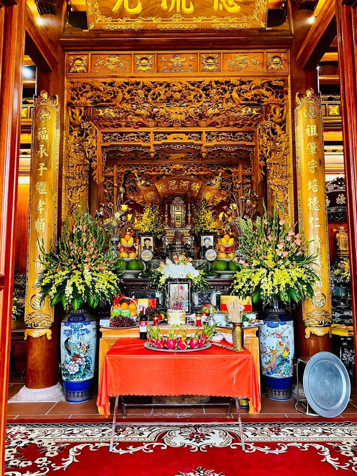 Ngôi nhà gỗ 5 gian gợi lên nét bình dị, 3 gian giữa thiết kế mở. Gian chính giữa là nơi thờ tự với án gian, cửa võng thờ, hoành phi câu đối được thếp vàng 24k. Ảnh: Happynest