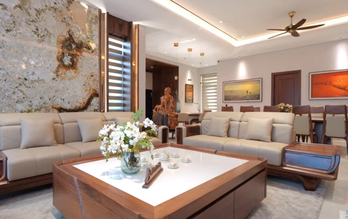 Toàn bộ không gian sinh hoạt chung (phòng khách, bếp và phòng ăn) sử dụng hai gam màu chủ đạo: kem trắng và gỗ óc chó. Ảnh chụp màn hình