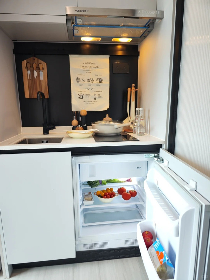Dãy tủ bếp âm tường chạy dọc tường bên phải, với tủ lạnh tích hợp, bồn rửa và khu vực nấu nướng được bố trí liên hoàn – tiện dụng và tiết kiệm diện tích tối đa. Ảnh: Sohu