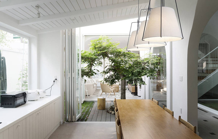 Hệ cửa được mở rộng tối đa để đón sáng, gió, và kết nối các tầng với nhau một cách liền mạch. Ảnh: Goku