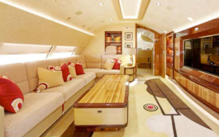 Phòng khách ở tầng trên của máy bay Boeing 747-8 có ghế sofa hình chữ L, giá sách âm tường và TV màn hình lớn. Ảnh: AMAC