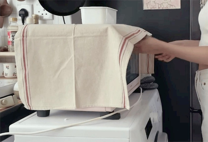 Mặt bàn bếp được kéo dài, máy giặt và lò nướng nhỏ được xếp chồng lên nhau ở cuối. Tủ lạnh đặt trong khoảng trống giữa phòng tắm và cửa phòng ngủ, giúp mặt bàn bếp trông rộng rãi hơn. Ảnh: Sohu