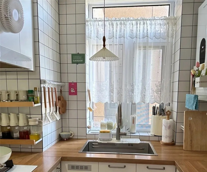 Phía trên còn có đèn chùm nhỏ tạo cảm giác dịu nhẹ. Góc cạnh ống khói được tận dụng lắp giá treo bát, dụng cụ bếp và gia vị. Ảnh: QQ