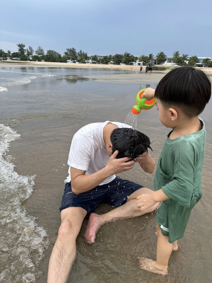 Cường Đô La ngồi chơi cùng con bên bờ biển. Ảnh: FBNV