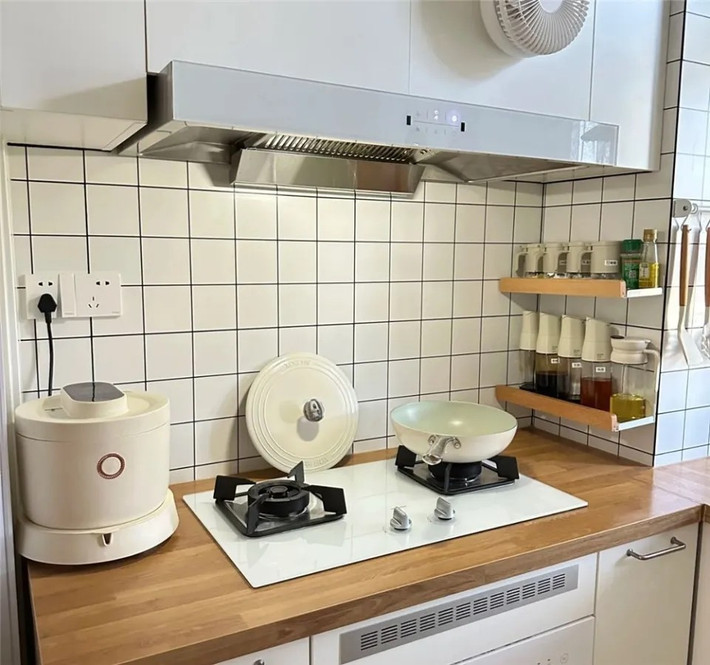 Để tránh nóng khi nấu vào mùa hè, gia chủ lắp một chiếc quạt điện nhỏ ngay cửa tủ bếp phía trên bếp. Ảnh: QQ