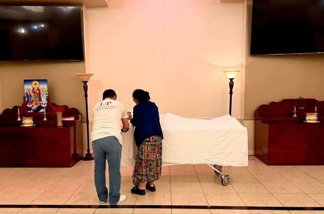 Mẹ Kasim Hoàng Vũ chỉnh sửa lại khăn phủ diện cho con trai tại nhà quàn. Ảnh: FBNV