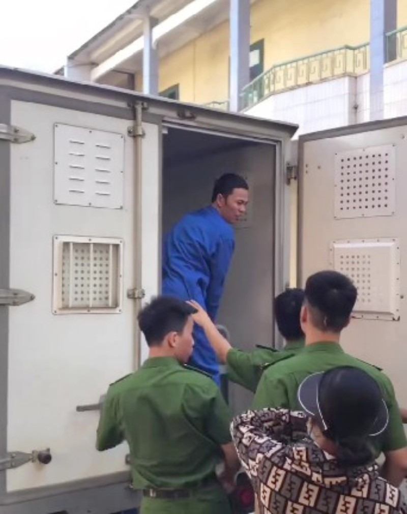 Bị cáo Thành quay đầu lại nhìn vợ ôm con nhỏ đứng khóc tiễn chồng lên xe thùng về trại tạm giam sau khi tòa sơ thẩm tuyên án.