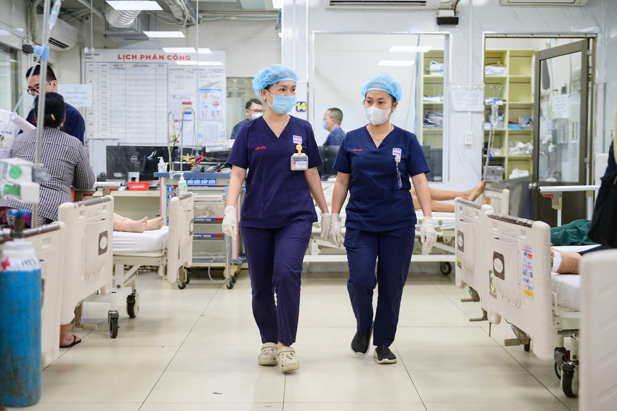 Lối đi trung tâm khoa Cấp cứu chật kín giường bệnh đặt song song hai bên, nhân viên y tế liên tục ra vào buồng bệnh.