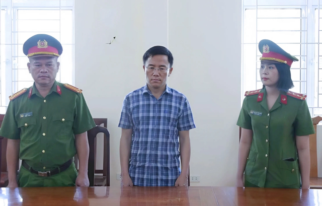 Ông Nguyễn Văn Hưng (đứng giữa), nghe cảnh sát đọc lệnh bắt. Ảnh: Công an cung cấp capture-8634.png